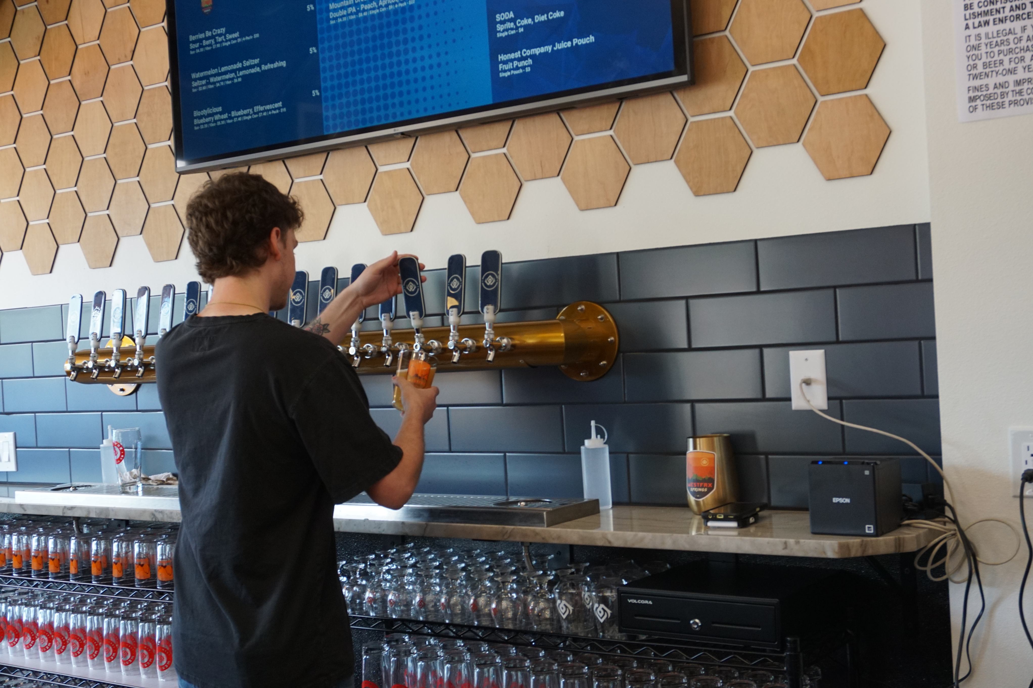 Person pouring beer from WestFax Springs taps